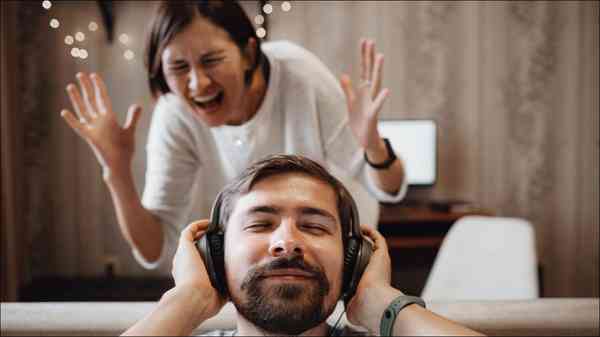 man-listening-headphones-woman-annoyed